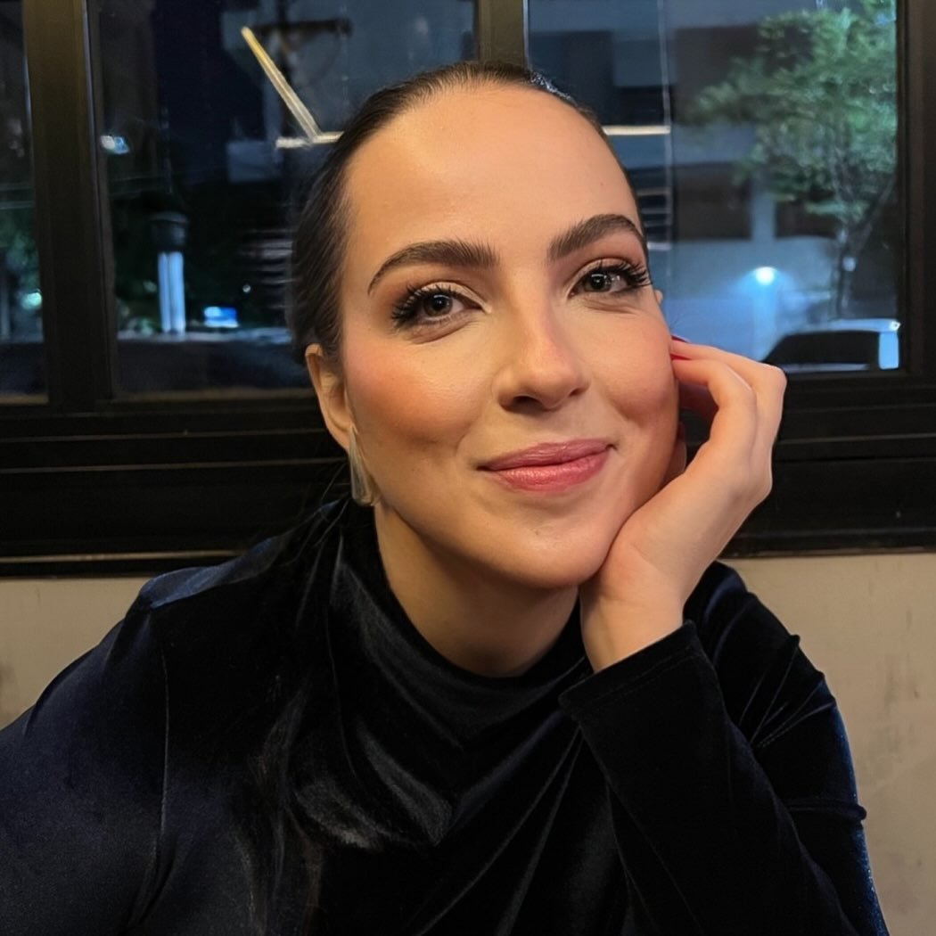 Dra. Giovanna Kobal, com a mão apoiada no rosto, em retrato com luz quente.